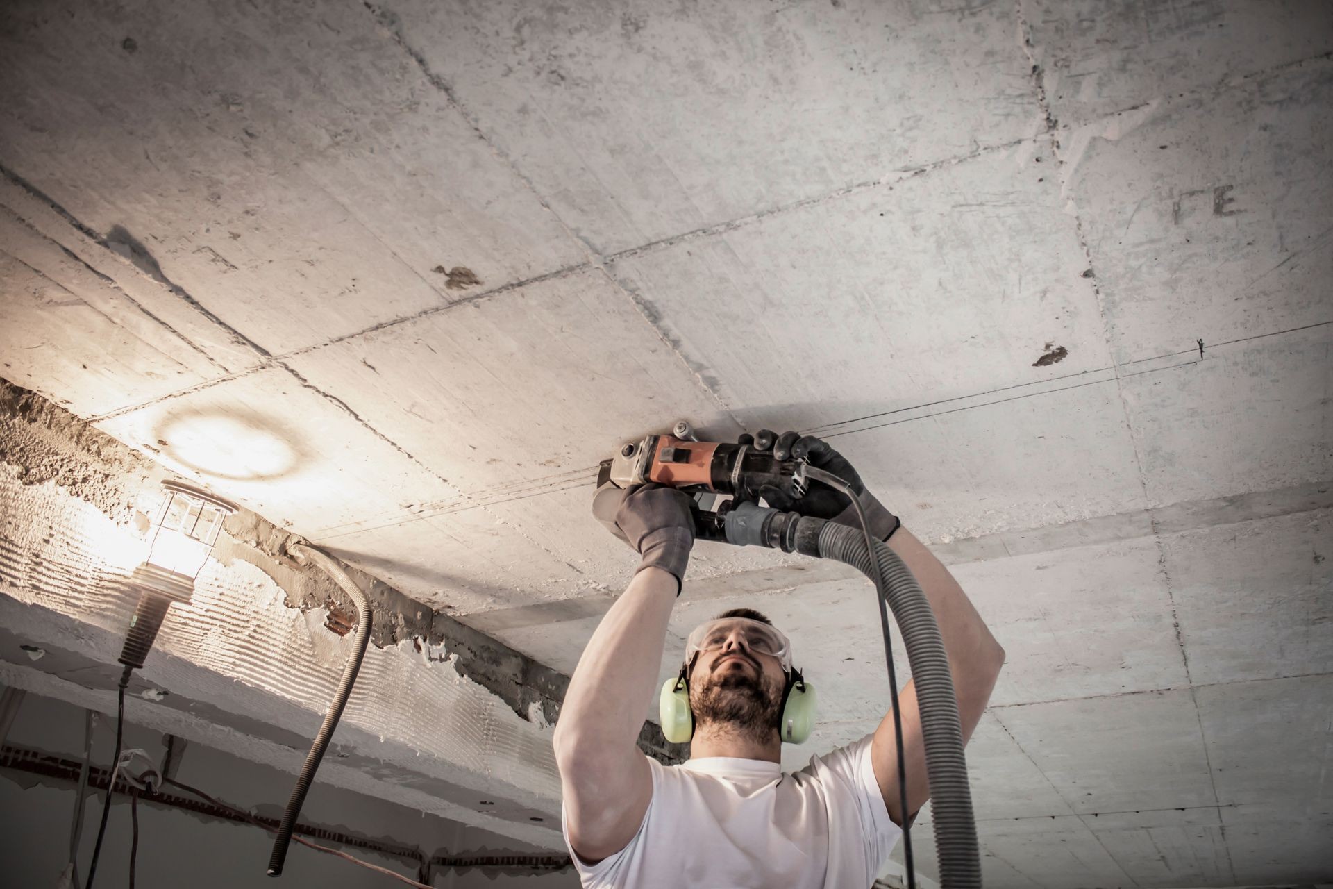 worker cuts slits in the concrete ceiling with electrical flex